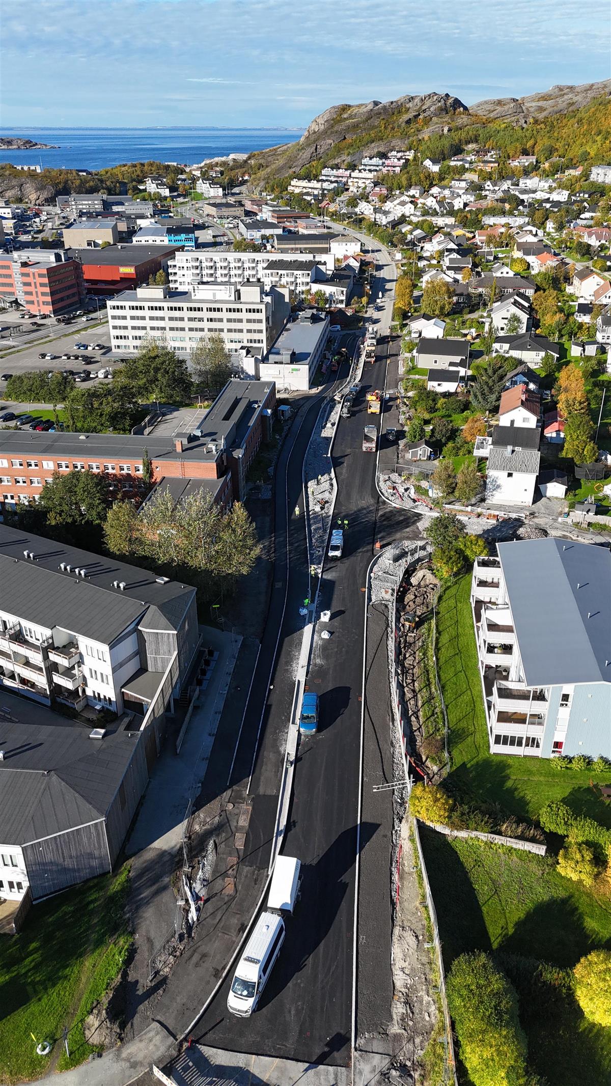 Gate med anleggsarbeid mellom boliger og næringsbygg. Dronefoto.  - Klikk for stort bilde